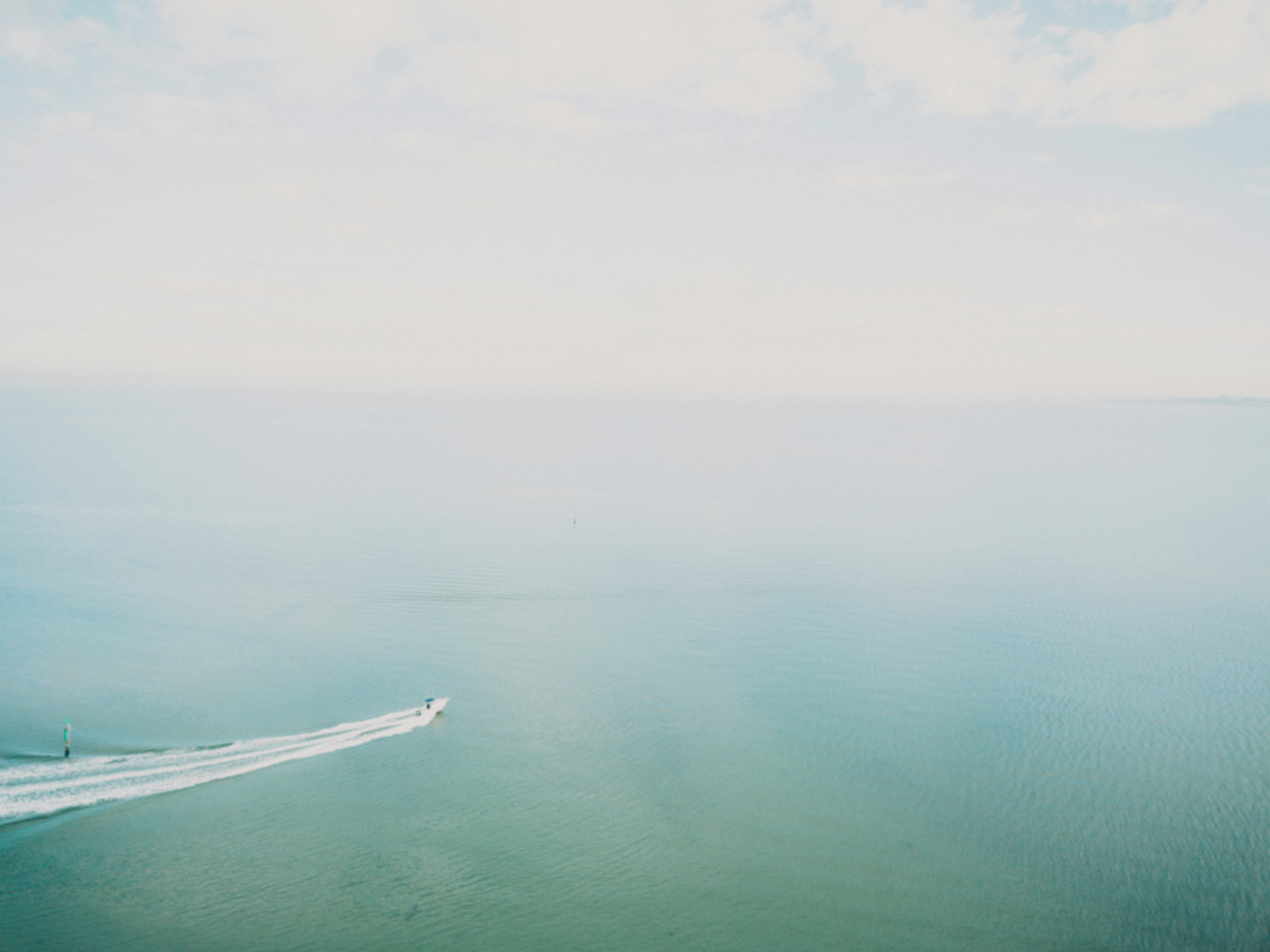 white boat on sea under white clouds during daytime